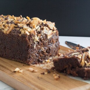 chocolate coconut banana bread on a wooden cutting board, with slices and knife alongside