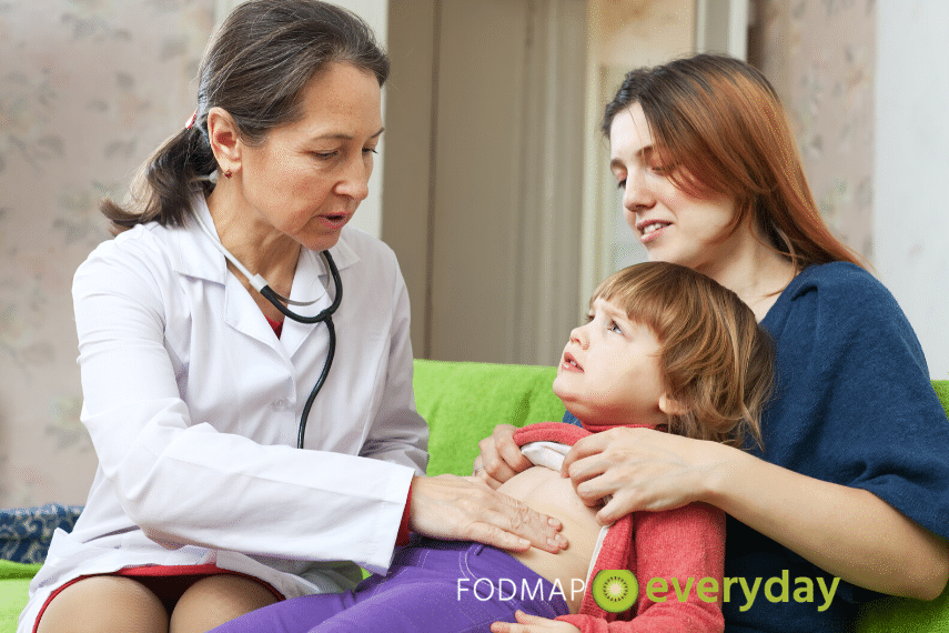 IBS in Children: It's important to obtain a proper diagnosis from a medical doctor. Doctor examining the belly of a young boy sitting in his mother's lap.
