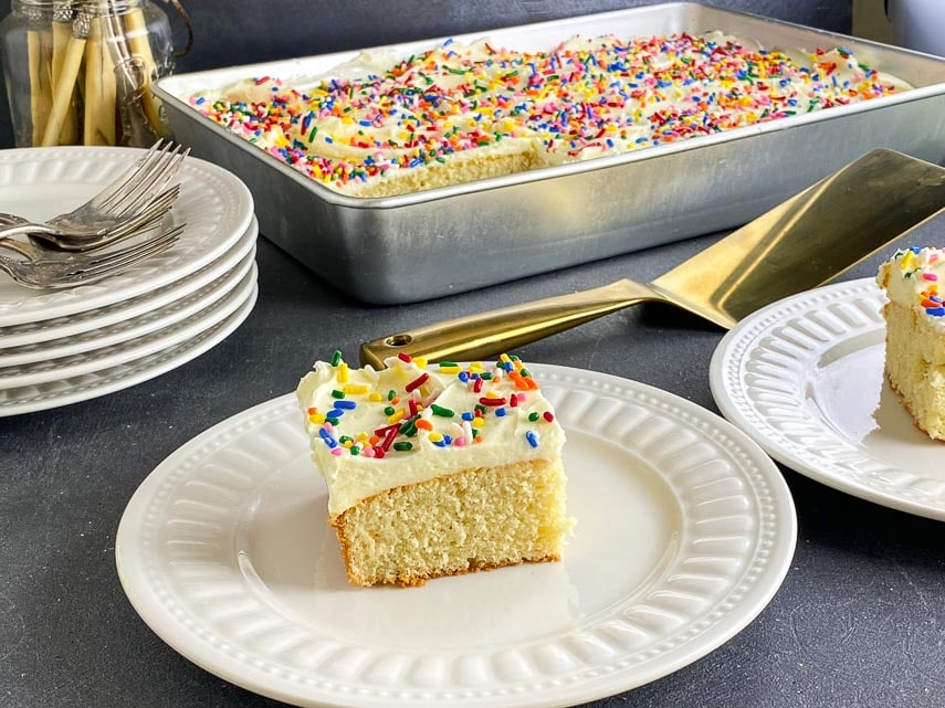 yellow cake square with white frosting and sprinkles on white plate