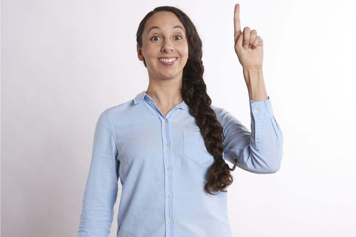woman in blue shirt holding finger up.