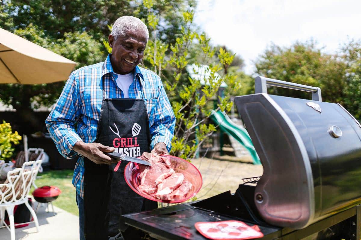 Man grilling steak; standing at grill. 