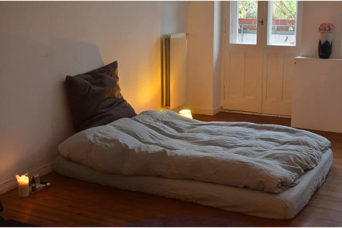 Mattress on floor; candles alongside. 