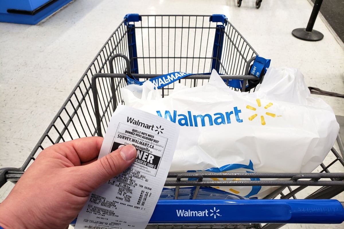 Walmart shopping cart with bag and receipt in Walmart store. Walmart is an American retail corporation that operates a chain of hypermarkets and discount stores.