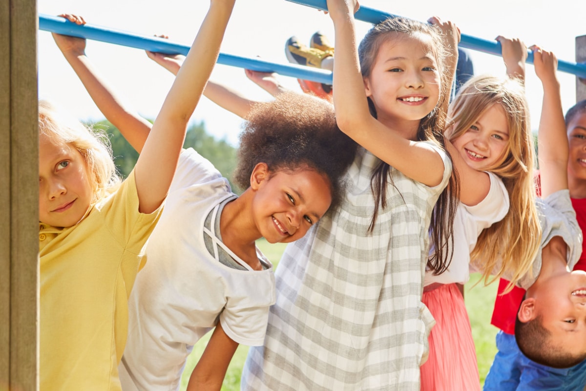 Multicultural kids as friends while doing gymnastics on a jungle gym.