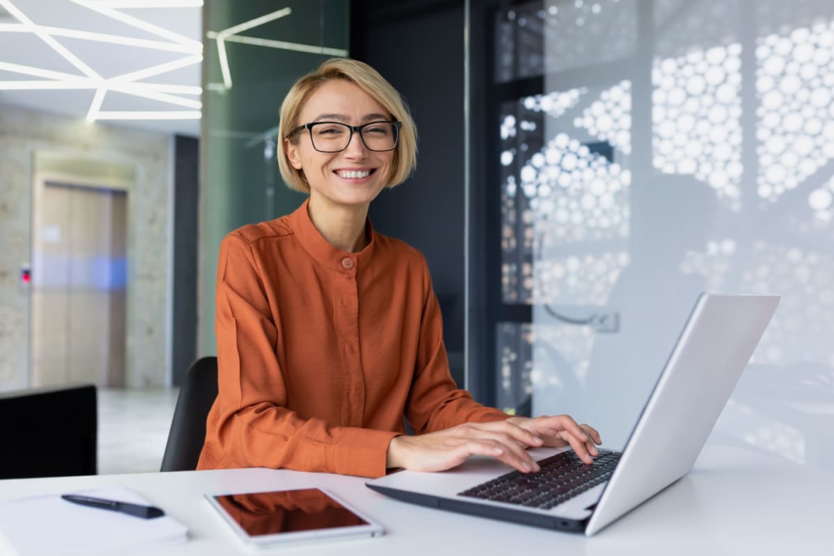 Young woman smiling working on a laptop.