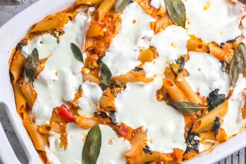 close-overhead-shot-of-baked-pasta-with-roasted-pumpkin-fresh-mozzarella-and-sage-in-white-baking-pan-on-rack.