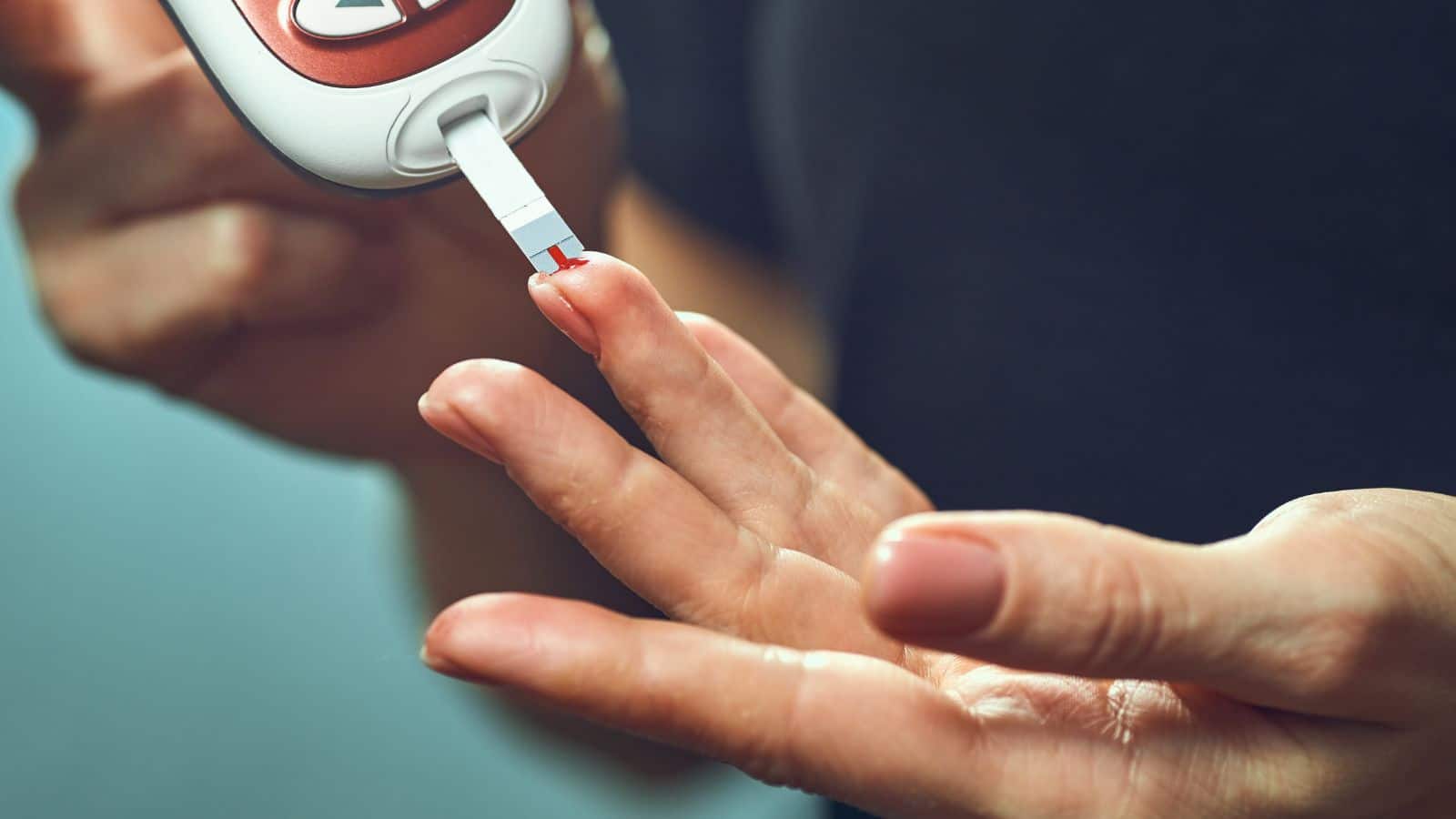 woman pricking her finger with a glucose monitoring device