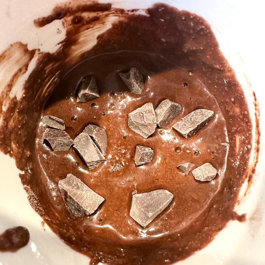 Mug cake batter with extra chocolate chunks in mug.